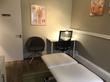 Treatment room in Haywards Heath with massage table - modern stylish interior design with grey green walls, small desk and consultation chairs
