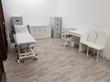 Treatment Room with massage table and consulting desk in Newcastle upon tyne Clinic, NE2 - Clean White colour scheme with wood floors