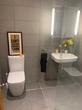 Toilet room with large charcoal grey tiles, sink & mirror