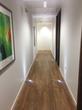 Modern contemporary corridor with wood floor and white walls, leading to treatment room for hire in Cannon Street, London, EC4